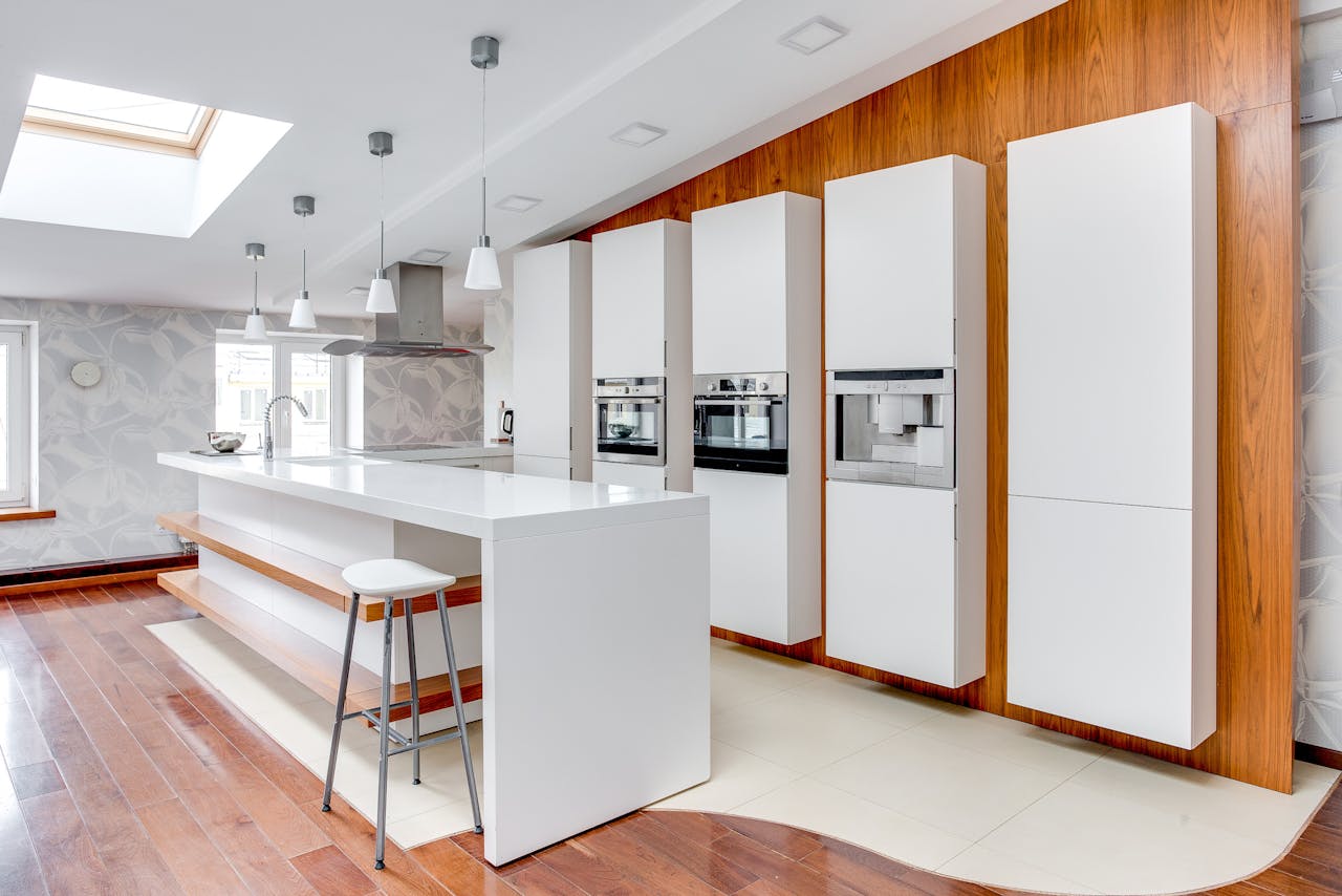 Sleek modern kitchen featuring white cabinets, wooden accents, and a spacious design highlighting minimalist aesthetics.